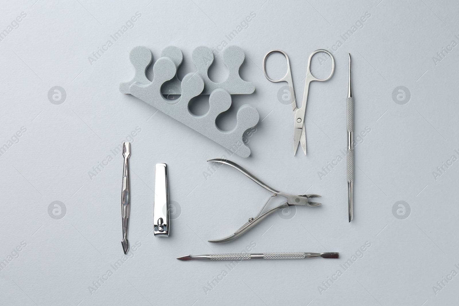 Photo of Set of pedicure tools on light grey background, flat lay