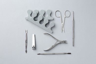 Photo of Set of pedicure tools on light grey background, flat lay