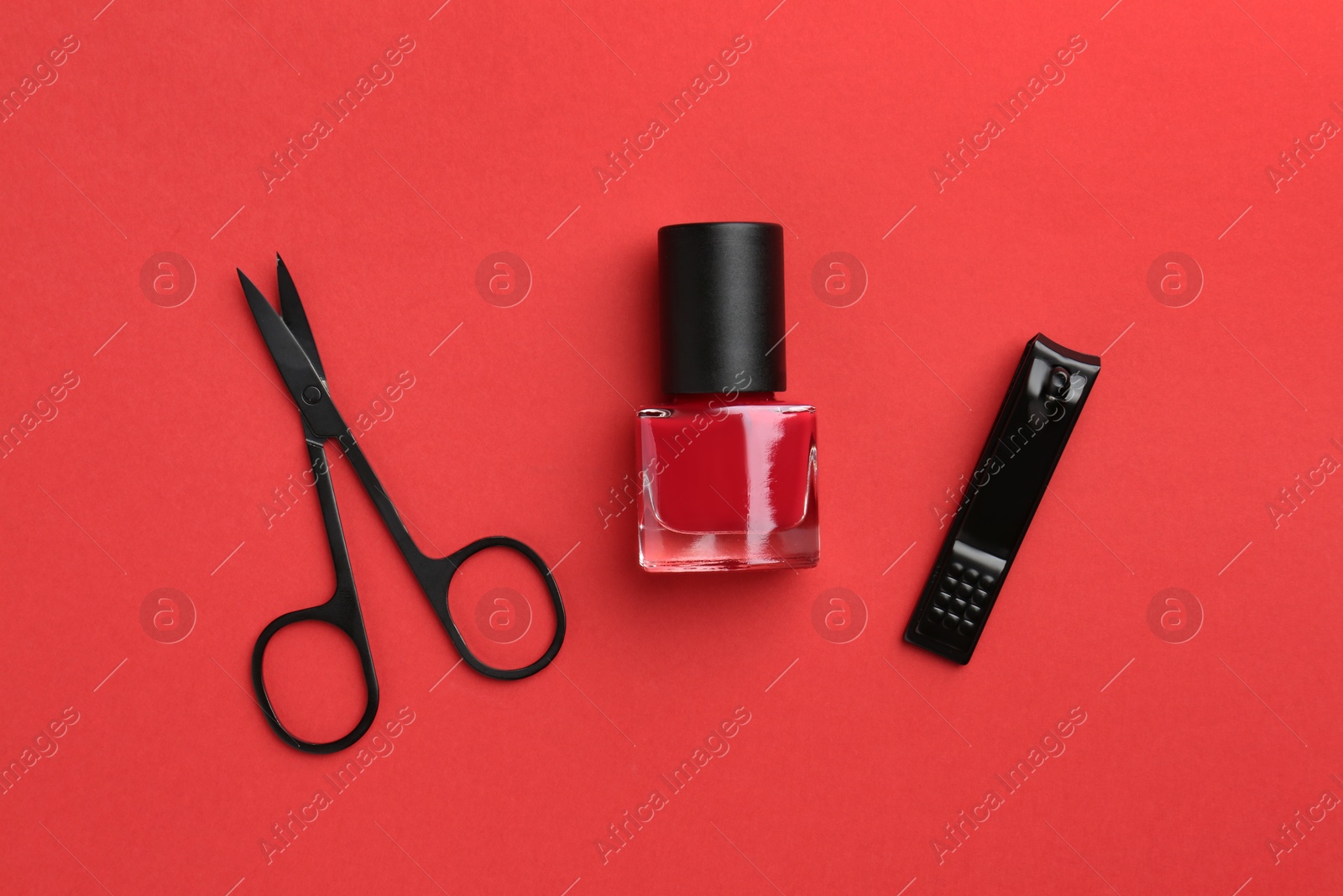 Photo of Set of pedicure tools on red background, flat lay