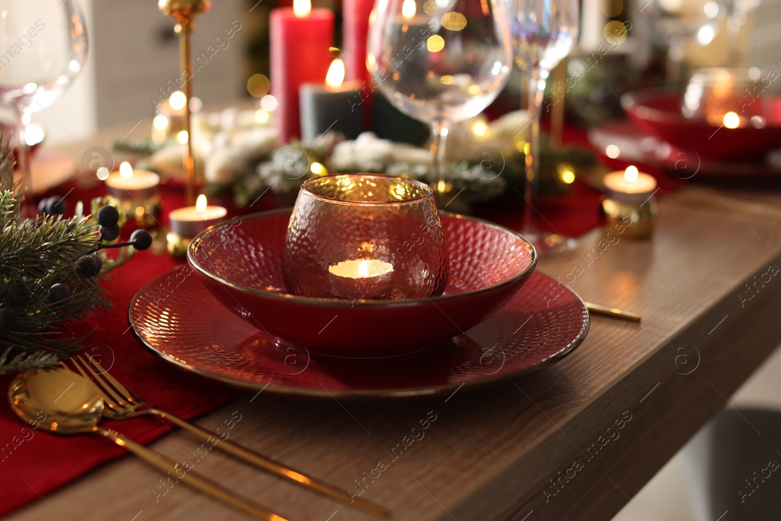 Photo of Christmas place setting with festive decor on wooden table in room, closeup