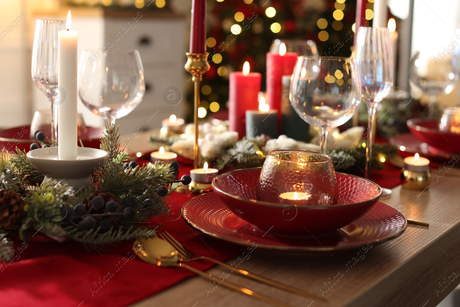 Photo of Christmas place setting with festive decor on wooden table in room, closeup