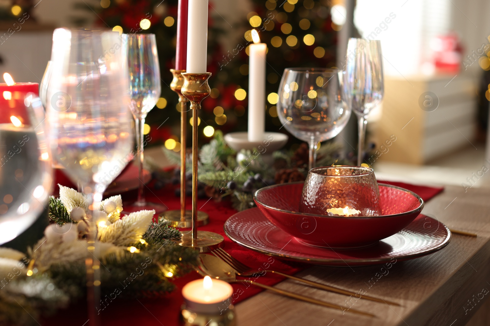 Photo of Christmas place setting with festive decor on wooden table in room, closeup