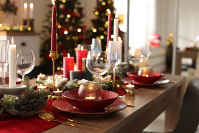 Photo of Christmas place setting with festive decor on wooden table in room