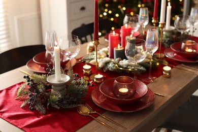 Photo of Christmas place setting with festive decor on wooden table in room