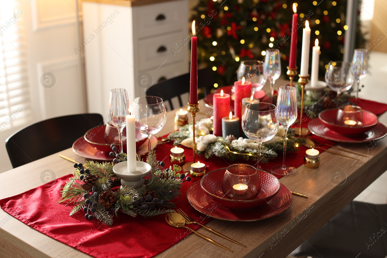 Photo of Christmas place setting with festive decor on wooden table in room