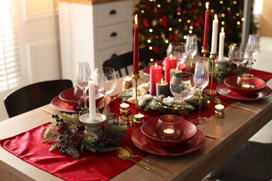 Photo of Christmas place setting with festive decor on wooden table in room