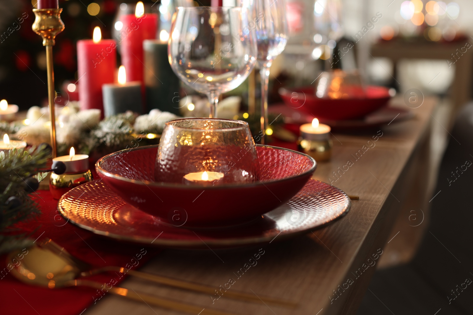 Photo of Christmas place setting with festive decor on wooden table in room, closeup