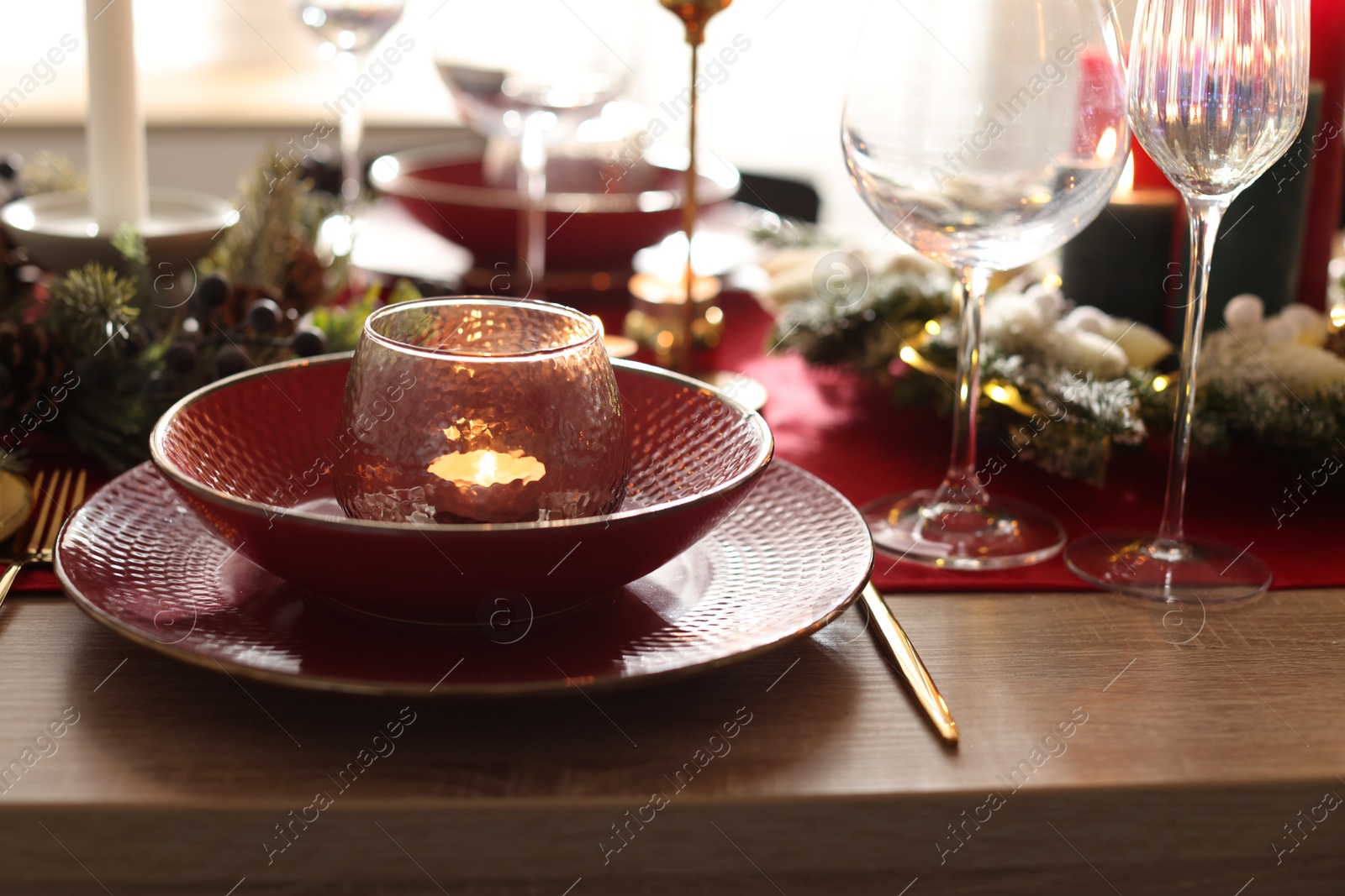 Photo of Christmas place setting with festive decor on wooden table in room, closeup