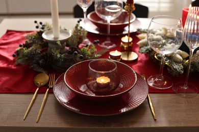 Photo of Christmas place setting with festive decor on wooden table in room