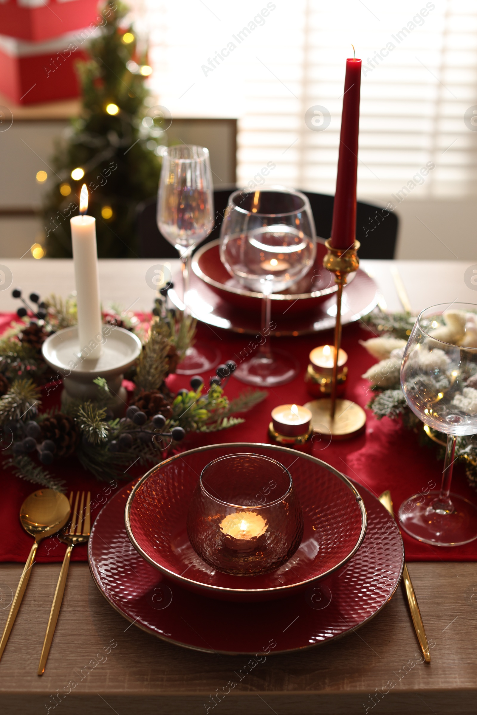 Photo of Christmas place setting with festive decor on wooden table in room