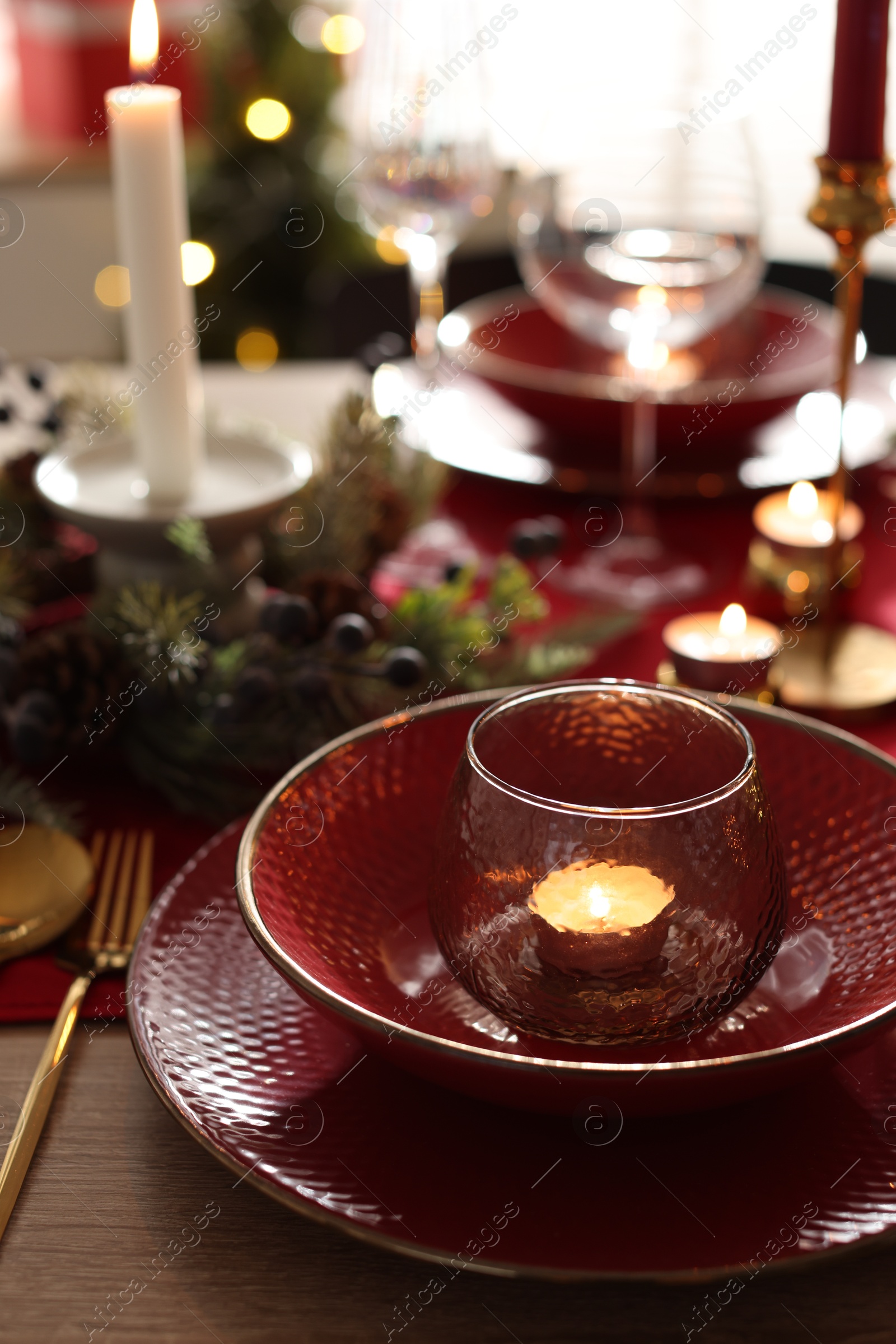 Photo of Christmas place setting with festive decor on wooden table in room, closeup