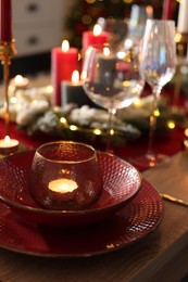 Photo of Christmas place setting with festive decor on wooden table in room, closeup