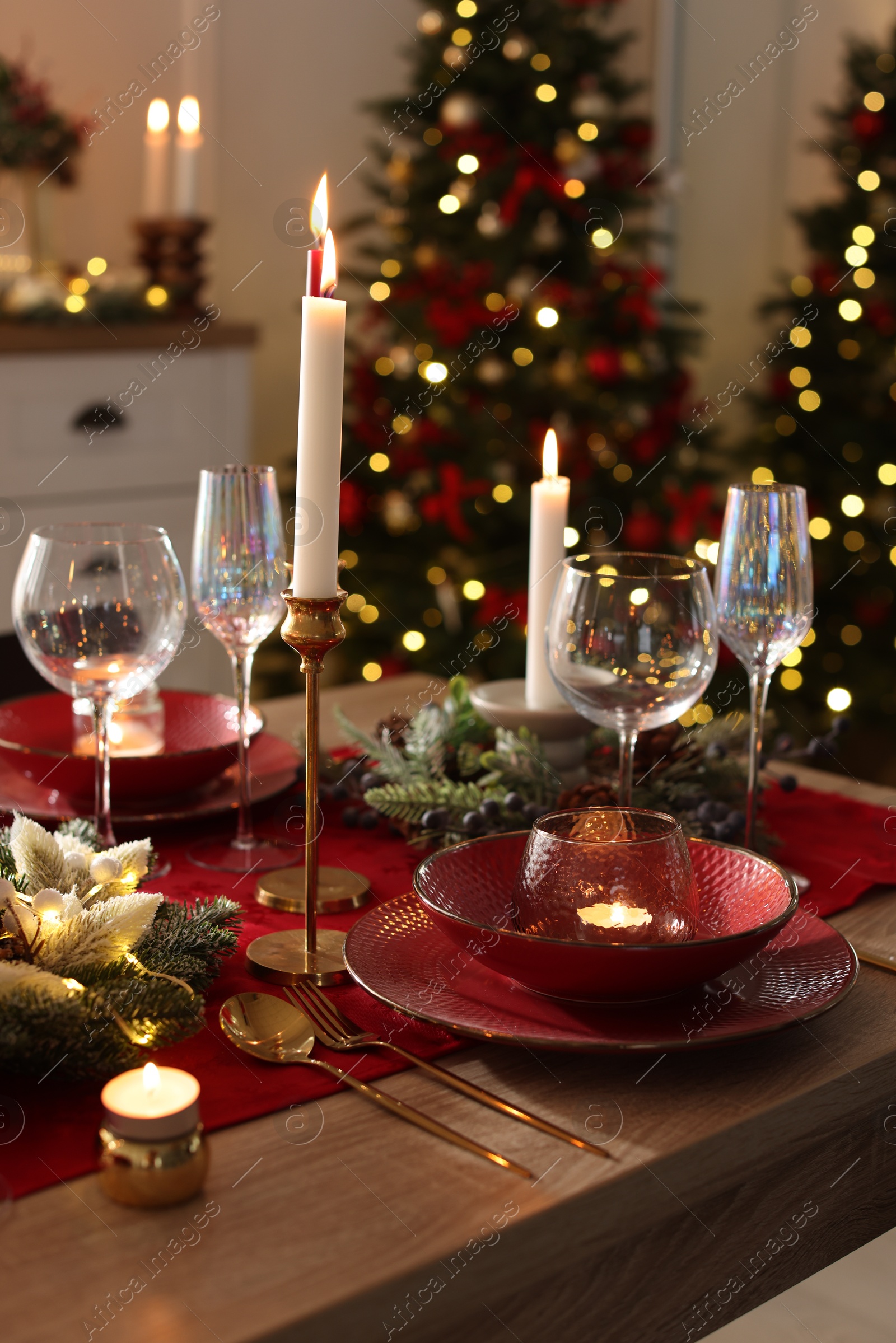 Photo of Christmas place setting with festive decor on wooden table in room