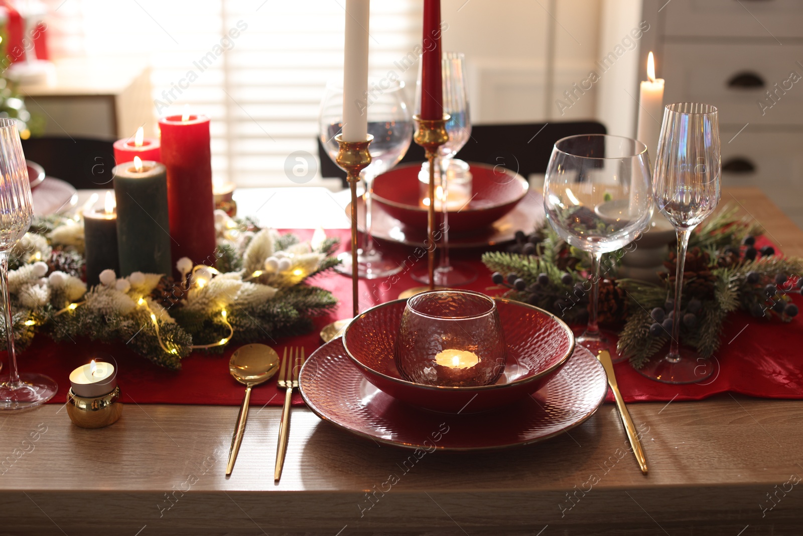 Photo of Christmas place setting with festive decor on wooden table in room