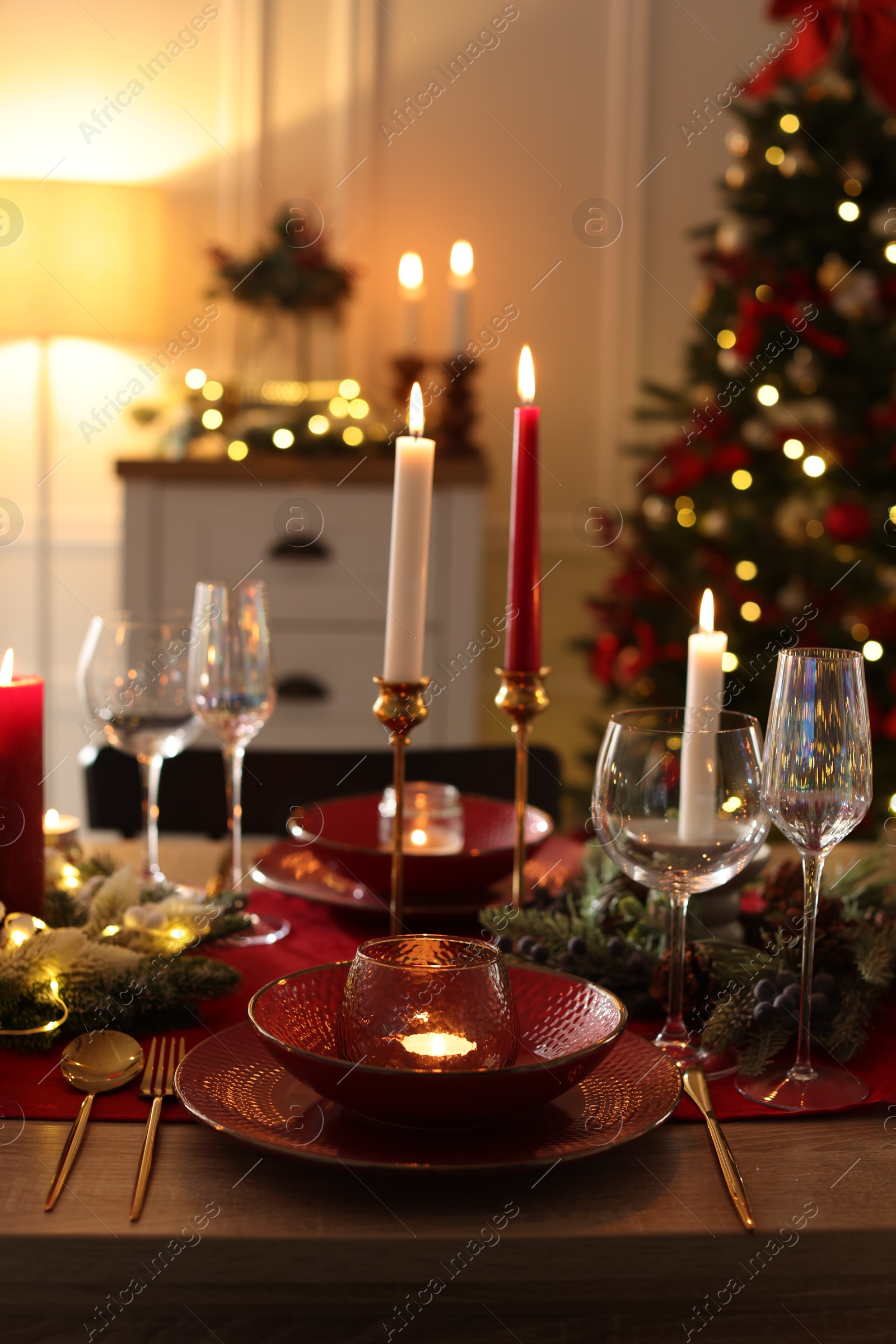 Photo of Christmas place setting with festive decor on wooden table in room