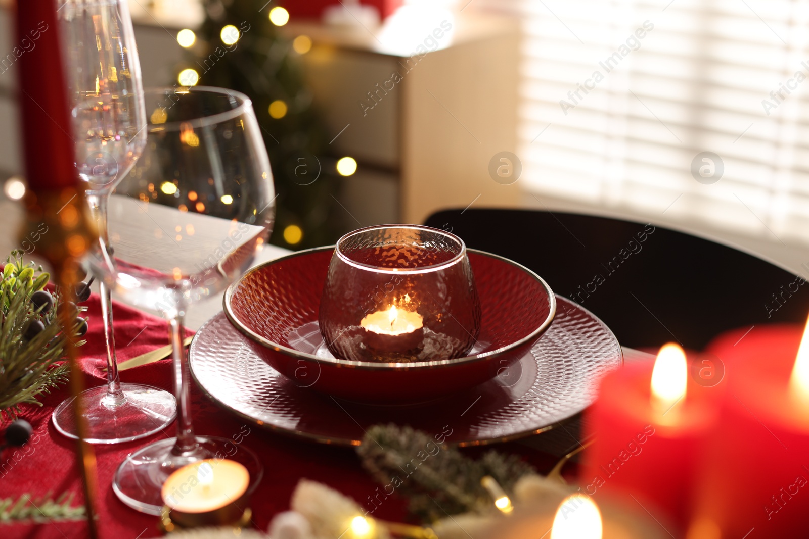 Photo of Christmas place setting with festive decor on table in room, closeup