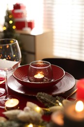 Photo of Christmas place setting with festive decor on table in room