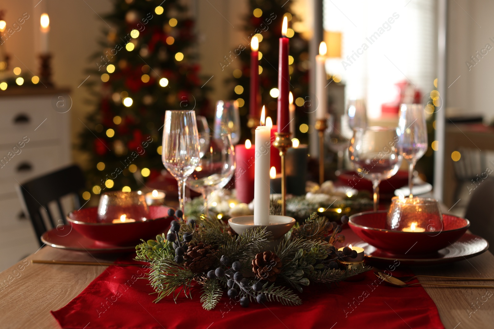 Photo of Christmas place setting with festive decor on wooden table in room