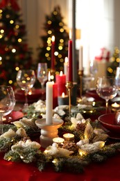 Photo of Christmas place setting with festive decor on table in room, closeup