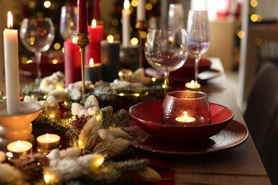 Photo of Christmas place setting with festive decor on wooden table in room, closeup