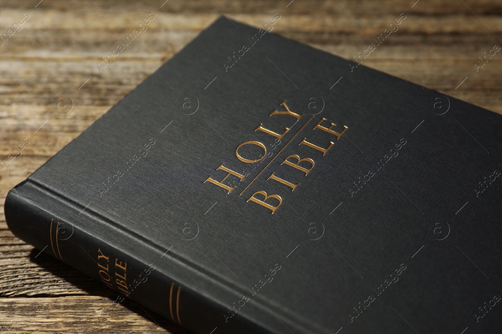 Photo of Hardcover Holy Bible on wooden table, closeup