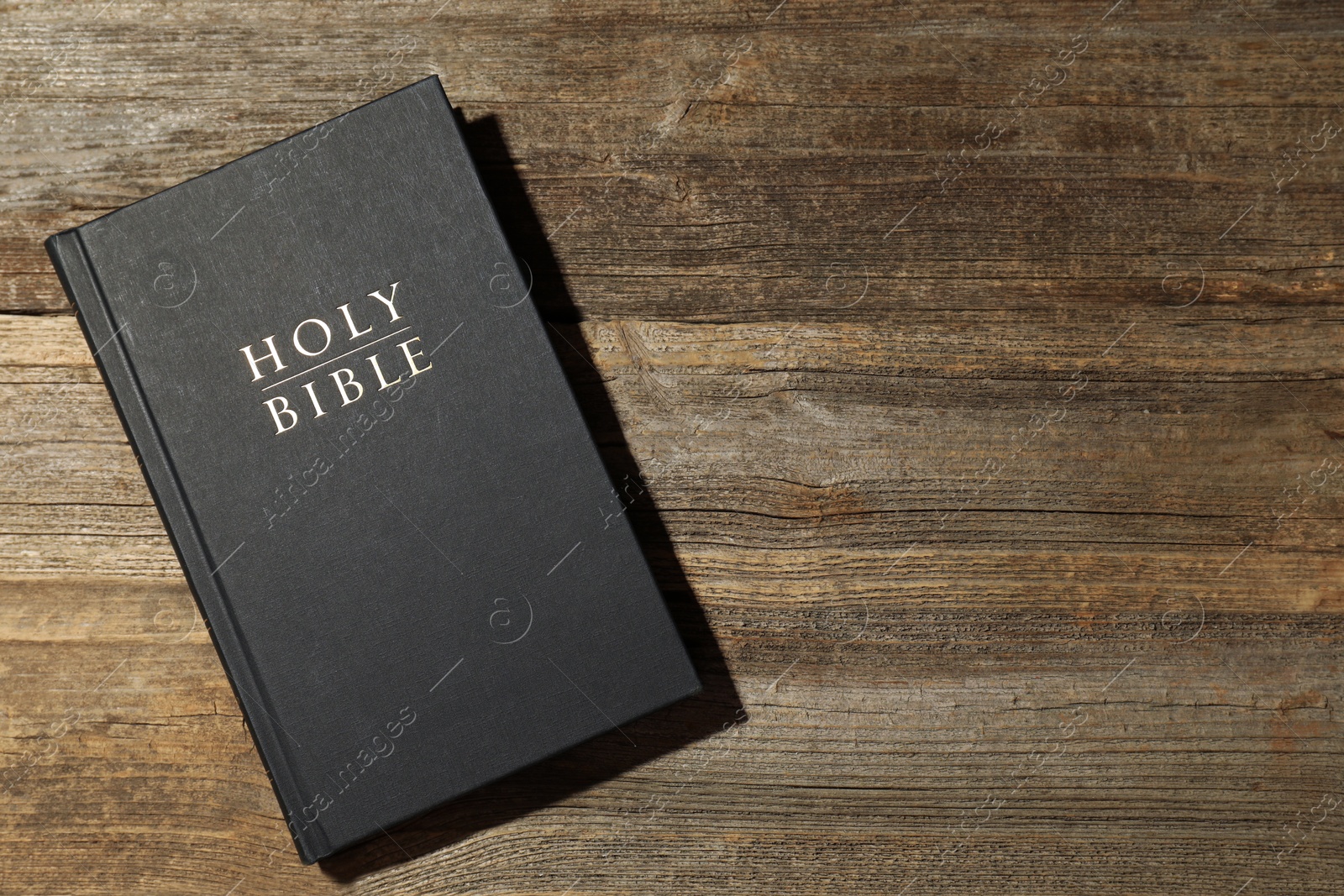 Photo of Hardcover Holy Bible on wooden table, top view. Space for text