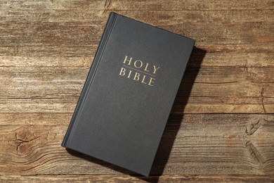 Photo of Hardcover Holy Bible on wooden table, top view