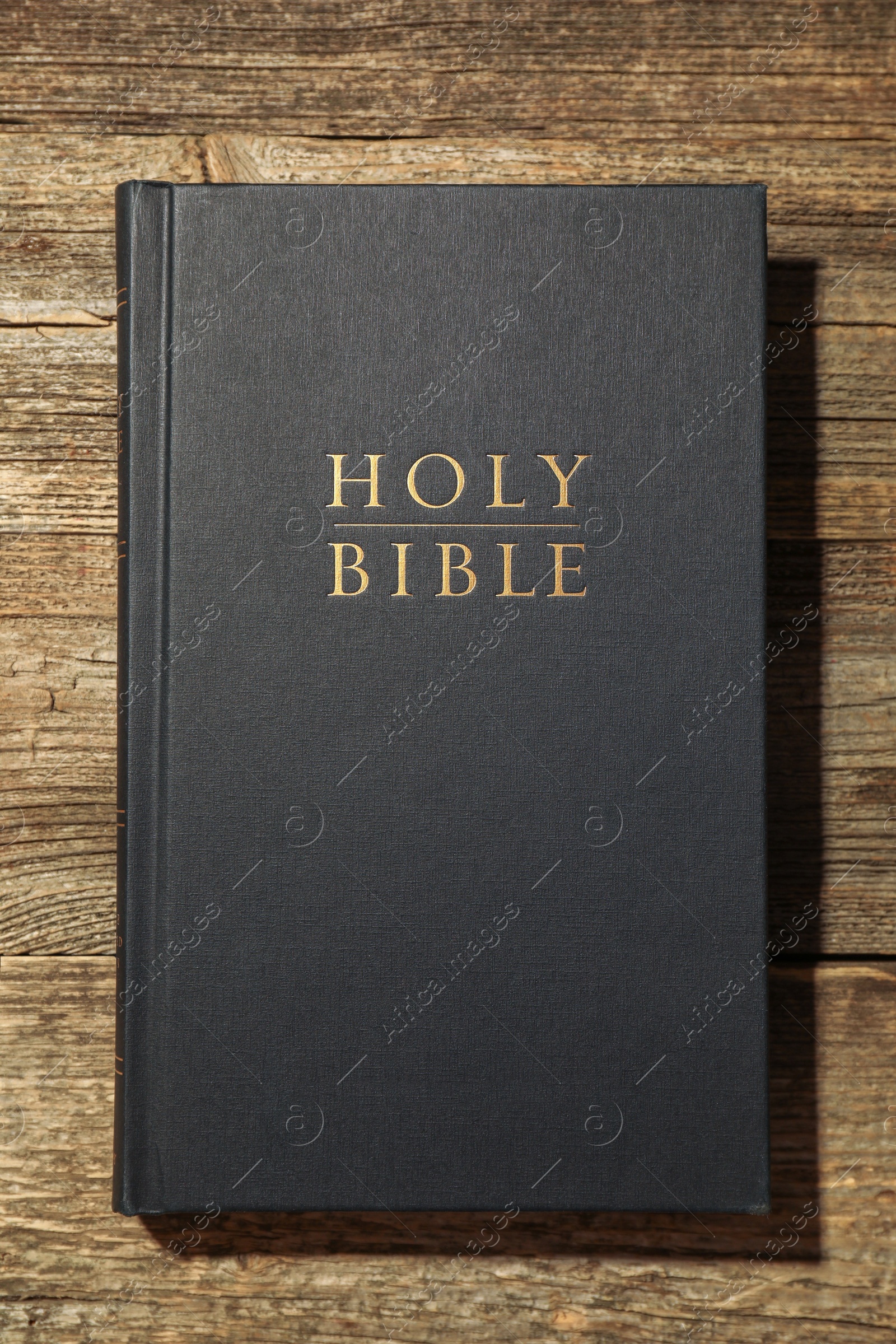 Photo of Hardcover Holy Bible on wooden table, top view