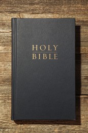 Photo of Hardcover Holy Bible on wooden table, top view