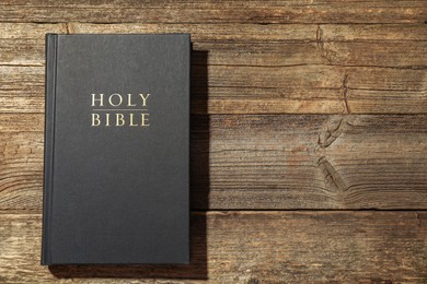 Photo of Hardcover Holy Bible on wooden table, top view. Space for text