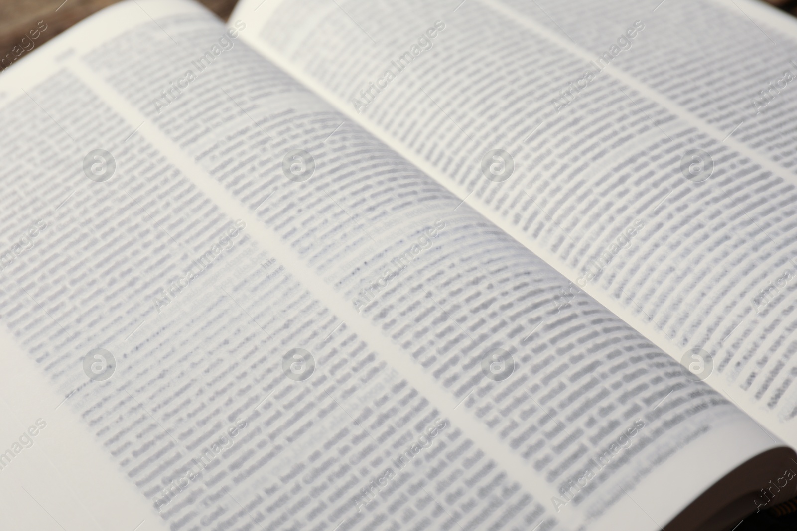 Photo of Open Holy Bible in English language on table, closeup