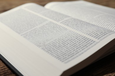 Open Holy Bible in English language on wooden table, closeup