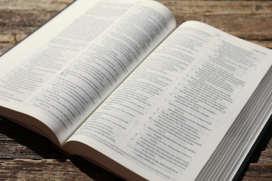 Photo of Open Holy Bible in English language on wooden table, closeup