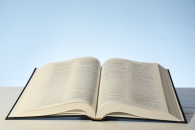 Photo of Open Holy Bible in English language on white table. Space for text