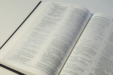 Photo of Open Holy Bible in English language on white table, closeup