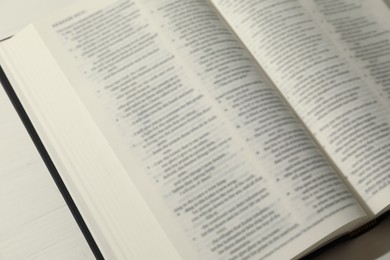 Photo of Open Holy Bible in English language on table, closeup