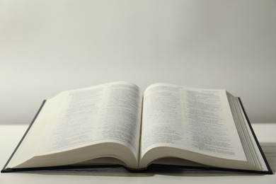 Photo of Open Holy Bible in English language on white table. Space for text