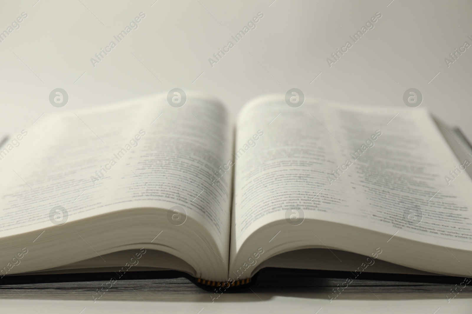 Photo of Open Holy Bible in English language on white table, closeup