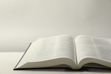 Photo of Open Holy Bible in English language on white table. Space for text