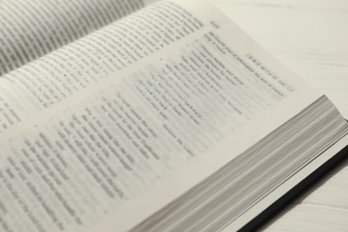 Photo of Open Holy Bible in English language on white table, closeup