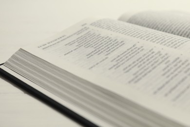 Photo of Open Holy Bible in English language on white table, closeup