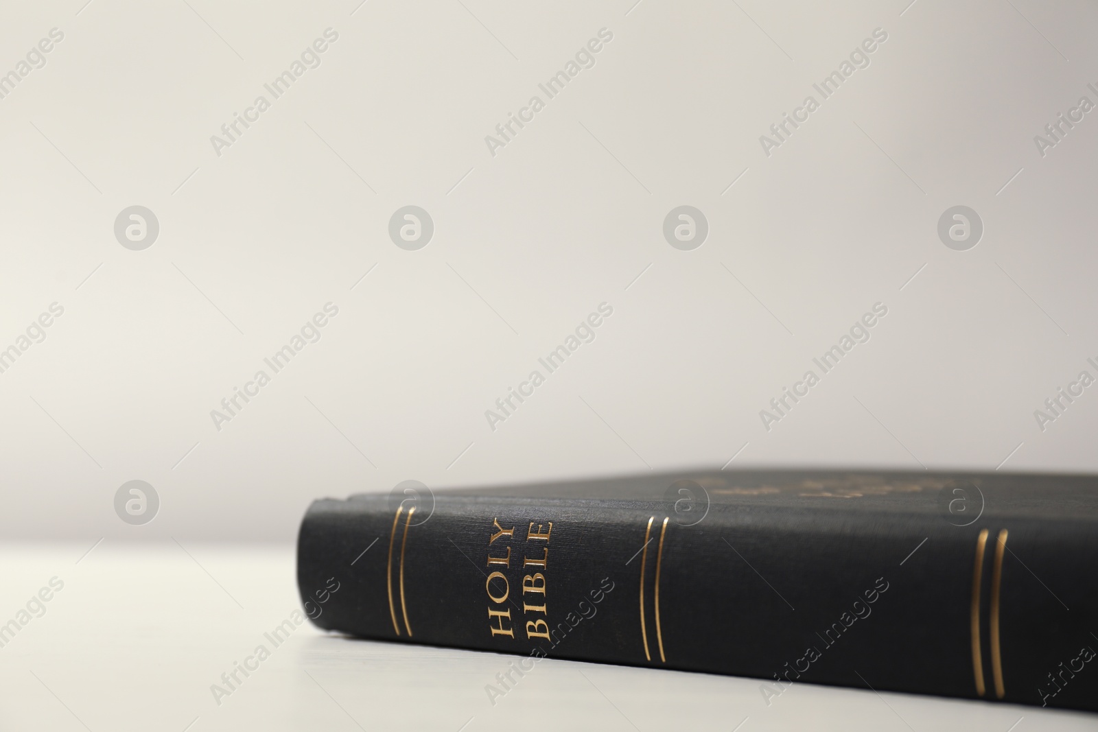 Photo of Hardcover Holy Bible on white table, closeup. Space for text