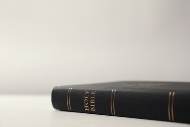 Photo of Hardcover Holy Bible on white table, closeup. Space for text