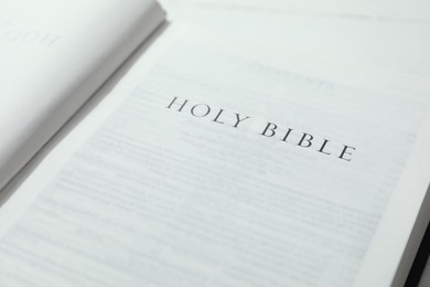 Photo of Open Holy Bible in English language on table, closeup