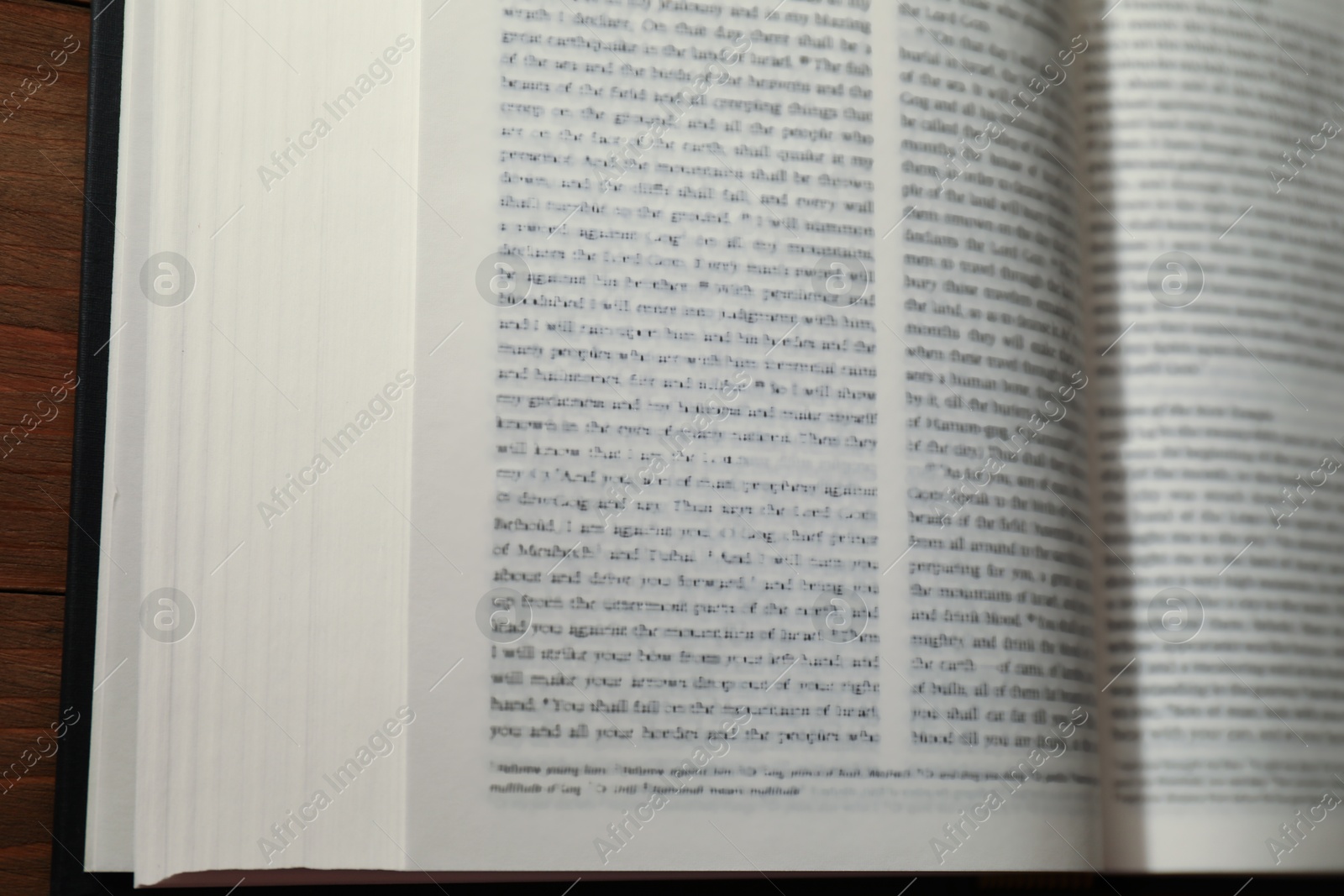 Photo of Open Holy Bible in English language on wooden table, closeup