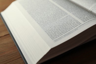 Open Holy Bible in English language on wooden table, closeup