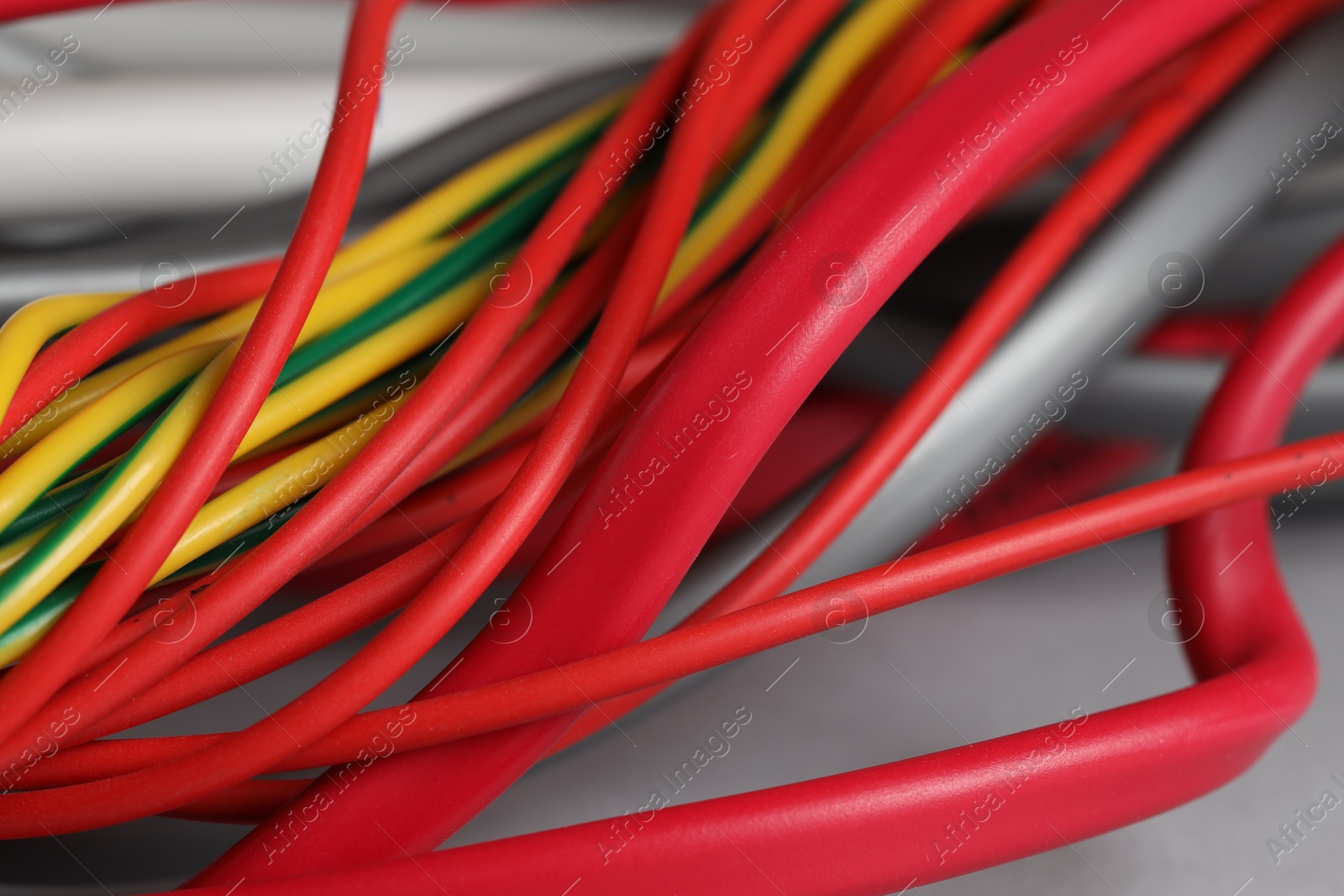 Photo of Many electrical wires on light grey background, closeup