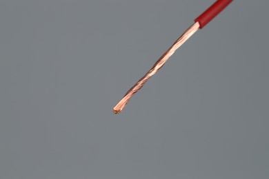 Photo of Red stripped electrical wire on light grey background, closeup