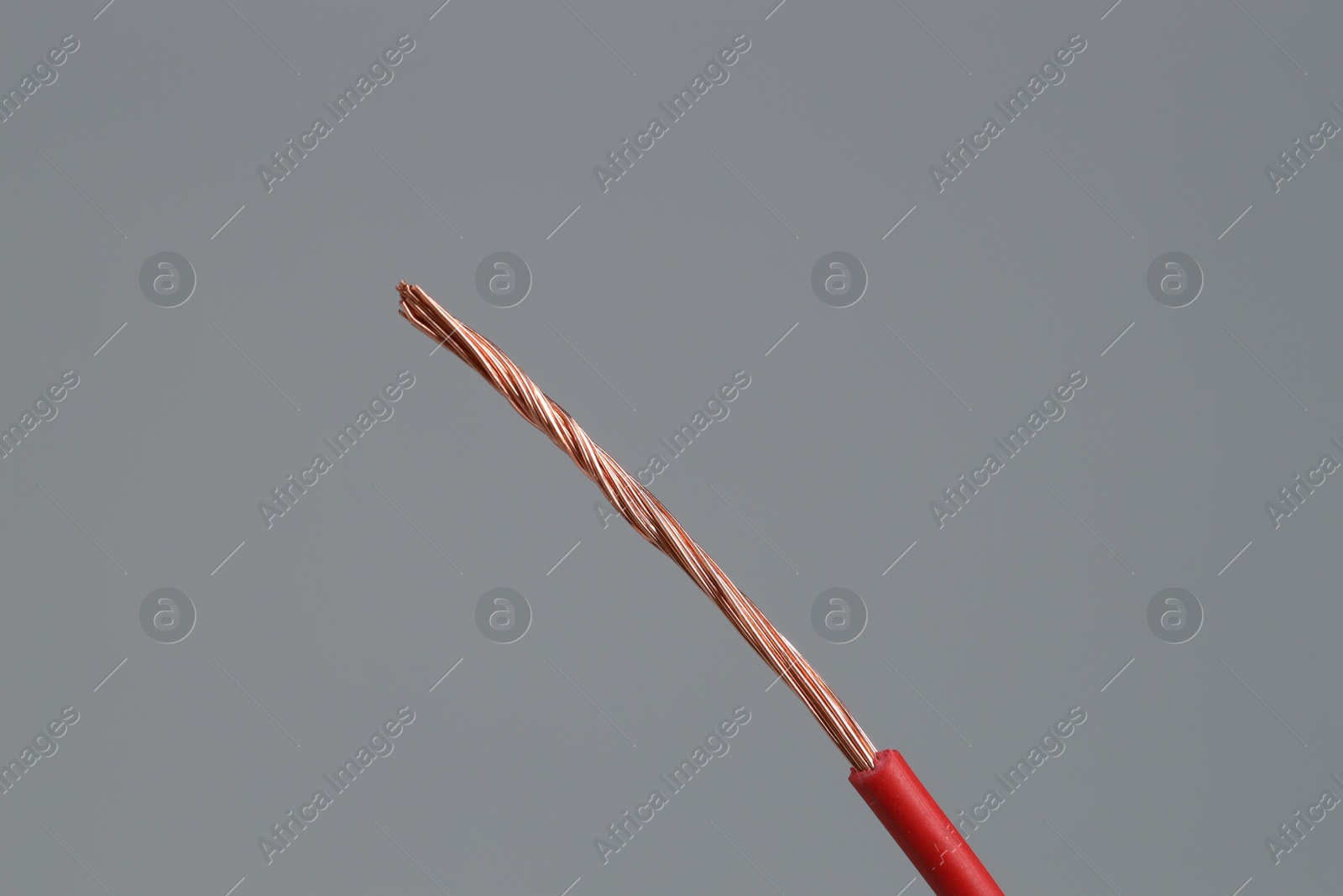 Photo of Red stripped electrical wire on light grey background, closeup