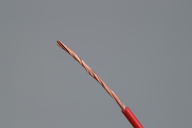 Photo of Red stripped electrical wire on light grey background, closeup